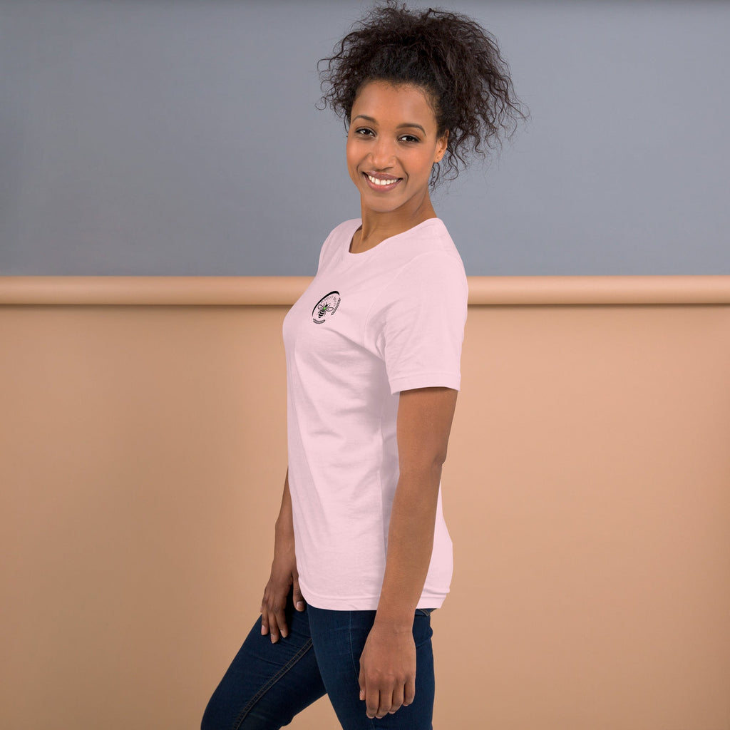 A woman wearing a light pink Barley Moon Botanicals t-shirt with a small bee and crescent moon logo on the chest.