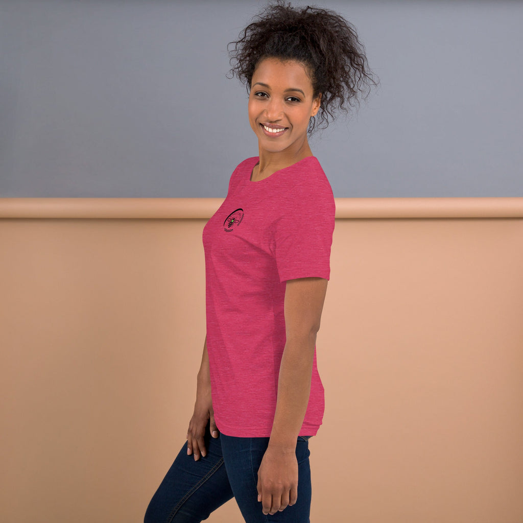 A woman wearing a pink Barley Moon Botanicals t-shirt with a small black bee and crescent moon logo on the chest.