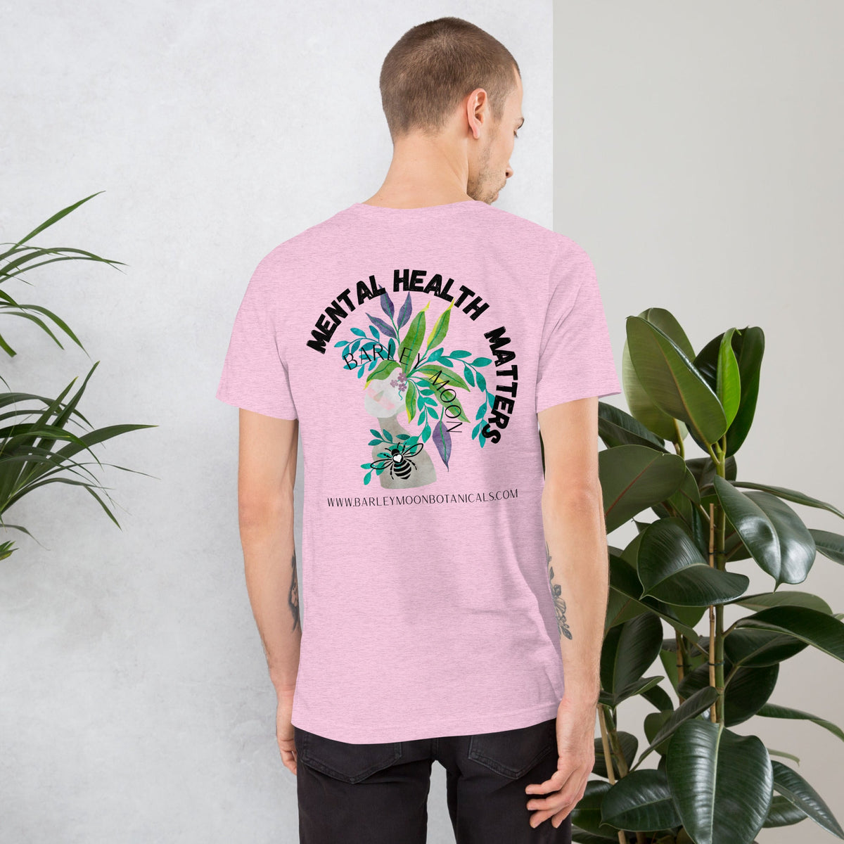 Man wearing a light pink Barley Moon Botanicals unisex t-shirt with botanical Mental Health Matters back print.