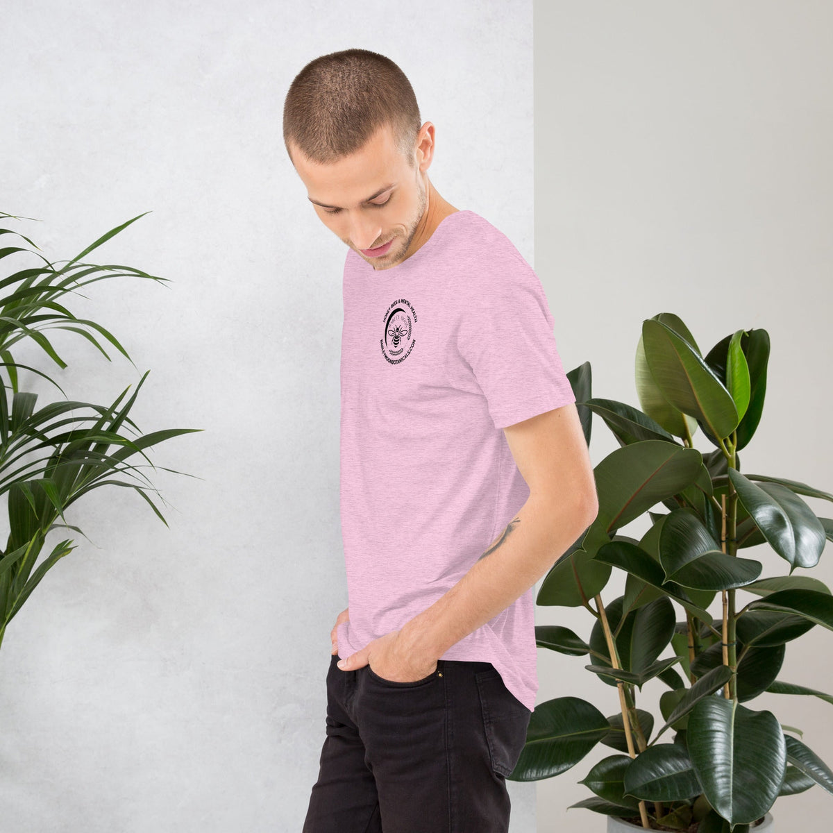A man wearing a light pink Barley Moon Botanicals unisex t-shirt with a small bee logo and mental health graphic.