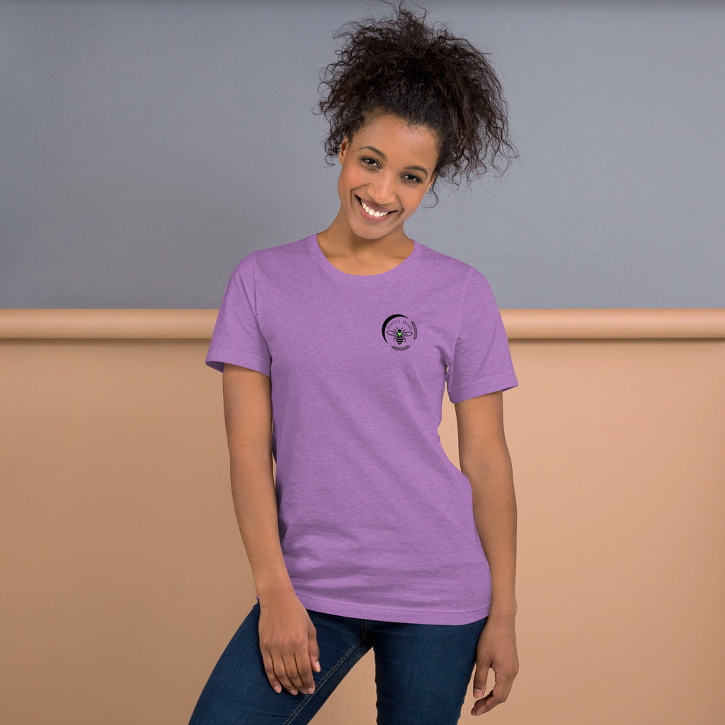 A smiling woman wearing a soft purple Barley Moon Botanicals t-shirt with a black bee and crescent moon logo.