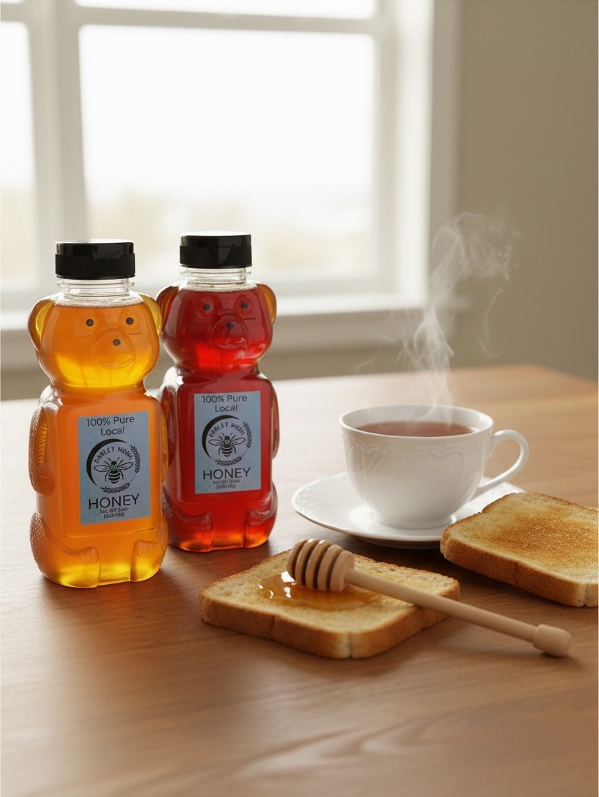 Barley Moon Botanicals raw honey in bear-shaped bottles next to a steaming cup of tea and toast with a honey dipper.
