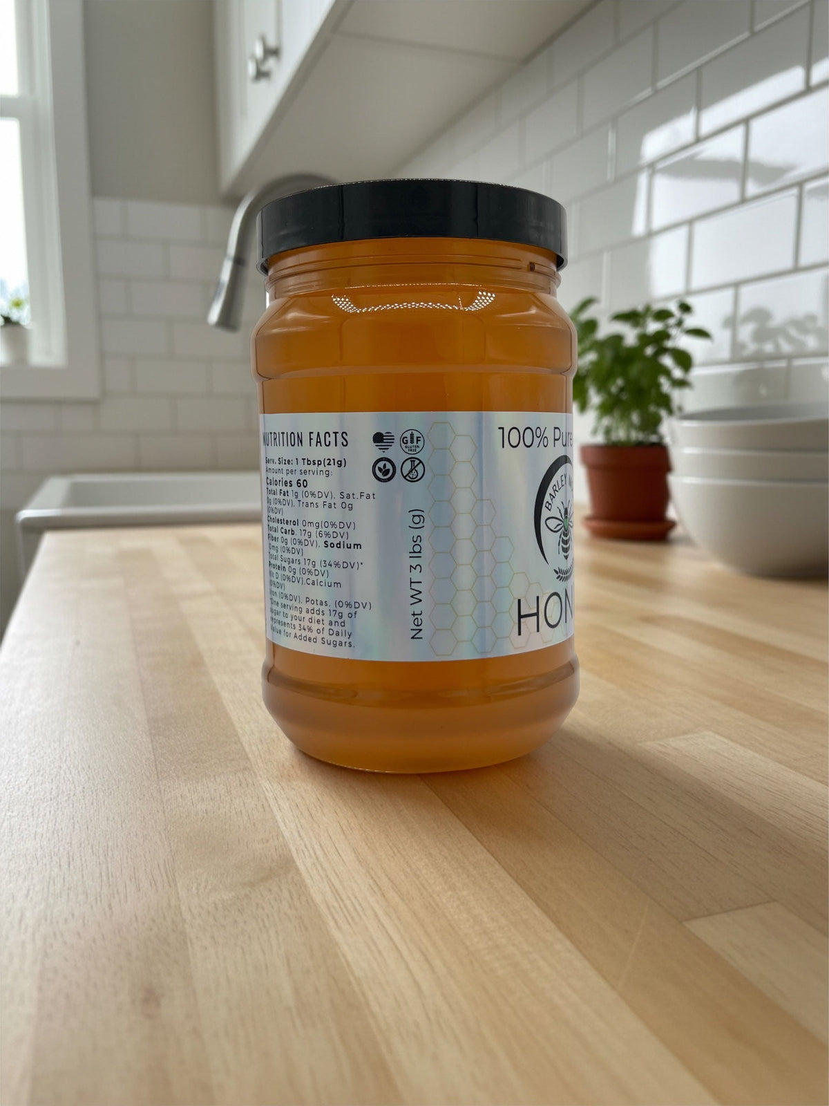 Barley Moon Botanicals 3lb jar of pure raw local honey with nutrition label on a wooden kitchen counter