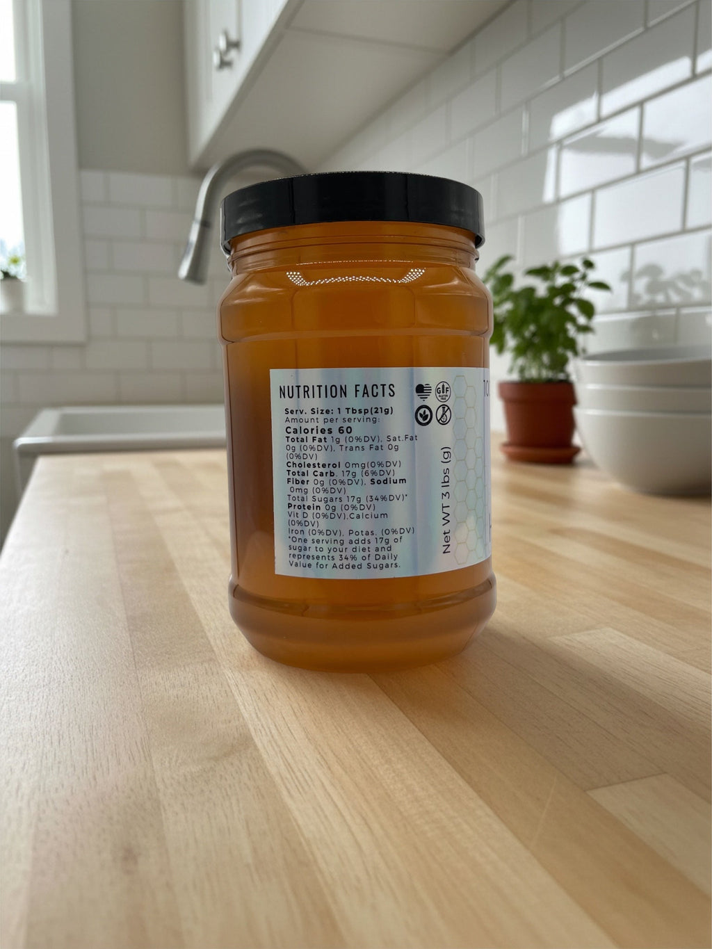 Barley Moon Botanicals 3lb jar of raw, unfiltered local honey showing the nutrition facts label on a kitchen counter.