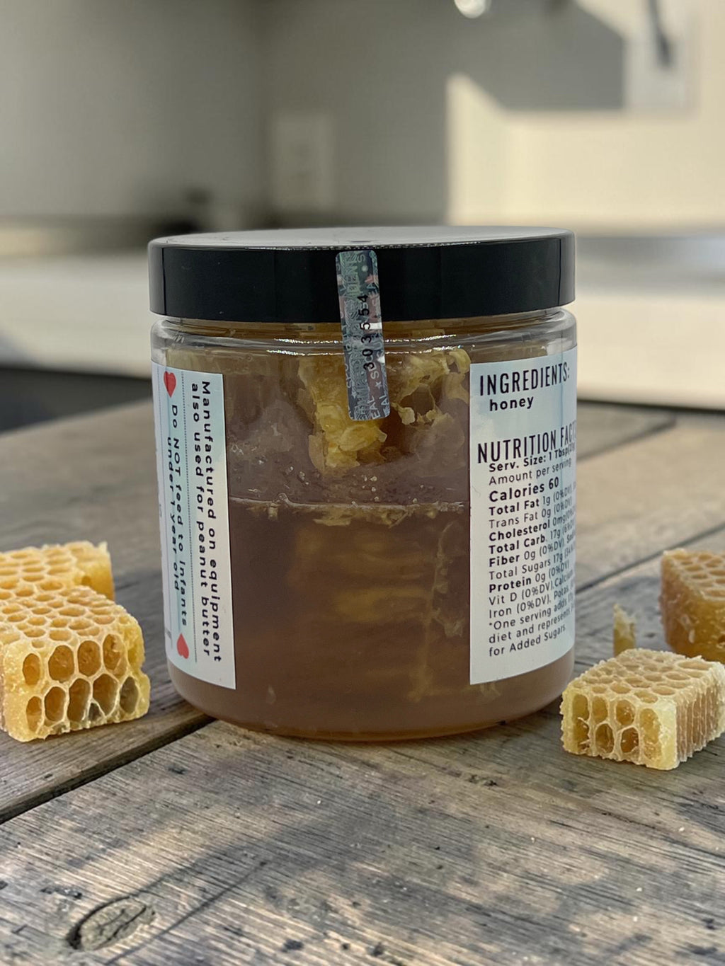 Barley Moon Botanicals raw honeycomb in a glass jar with golden honey and beeswax chunks on a rustic wooden table.