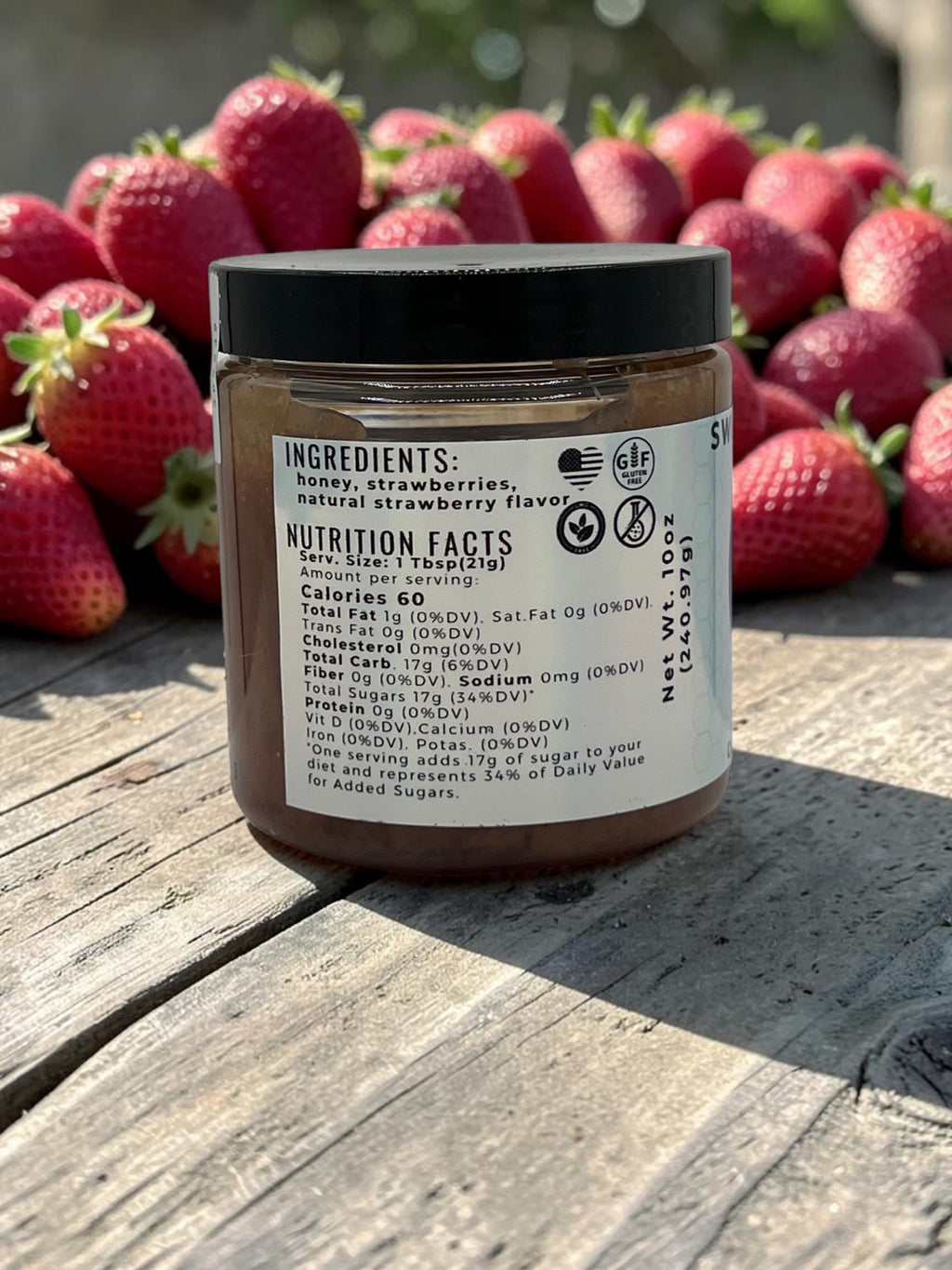 Barley Moon Botanicals Sweetie Berry creamed honey jar showing nutrition facts label against fresh strawberries