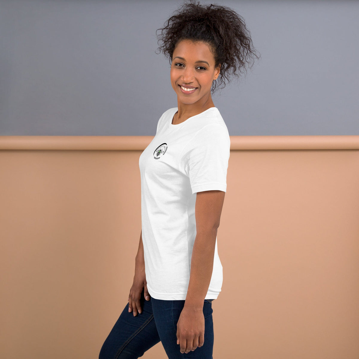 A woman wearing a white Barley Moon Botanicals t-shirt with a black bee and crescent moon logo on the chest.