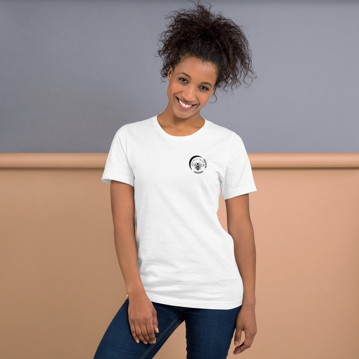 Smiling woman wearing a white Barley Moon Botanicals t-shirt with a black bee and crescent moon logo on the chest.