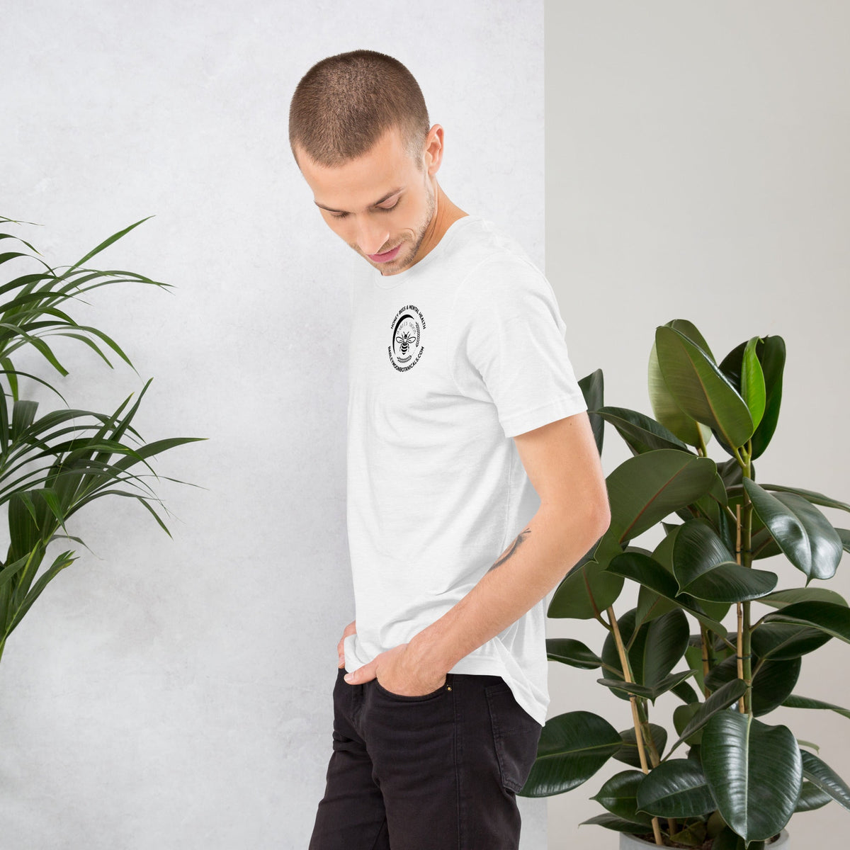 A man wearing a white Barley Moon Botanicals unisex t-shirt with a small bee and mental health graphic on the chest.
