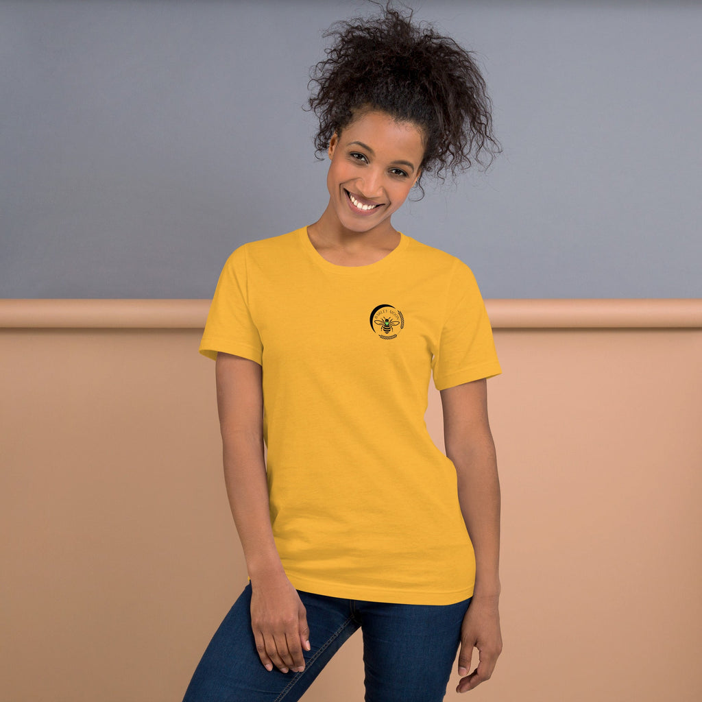 A smiling woman wearing a yellow Barley Moon Botanicals t-shirt with a black bee and crescent moon logo on the chest.