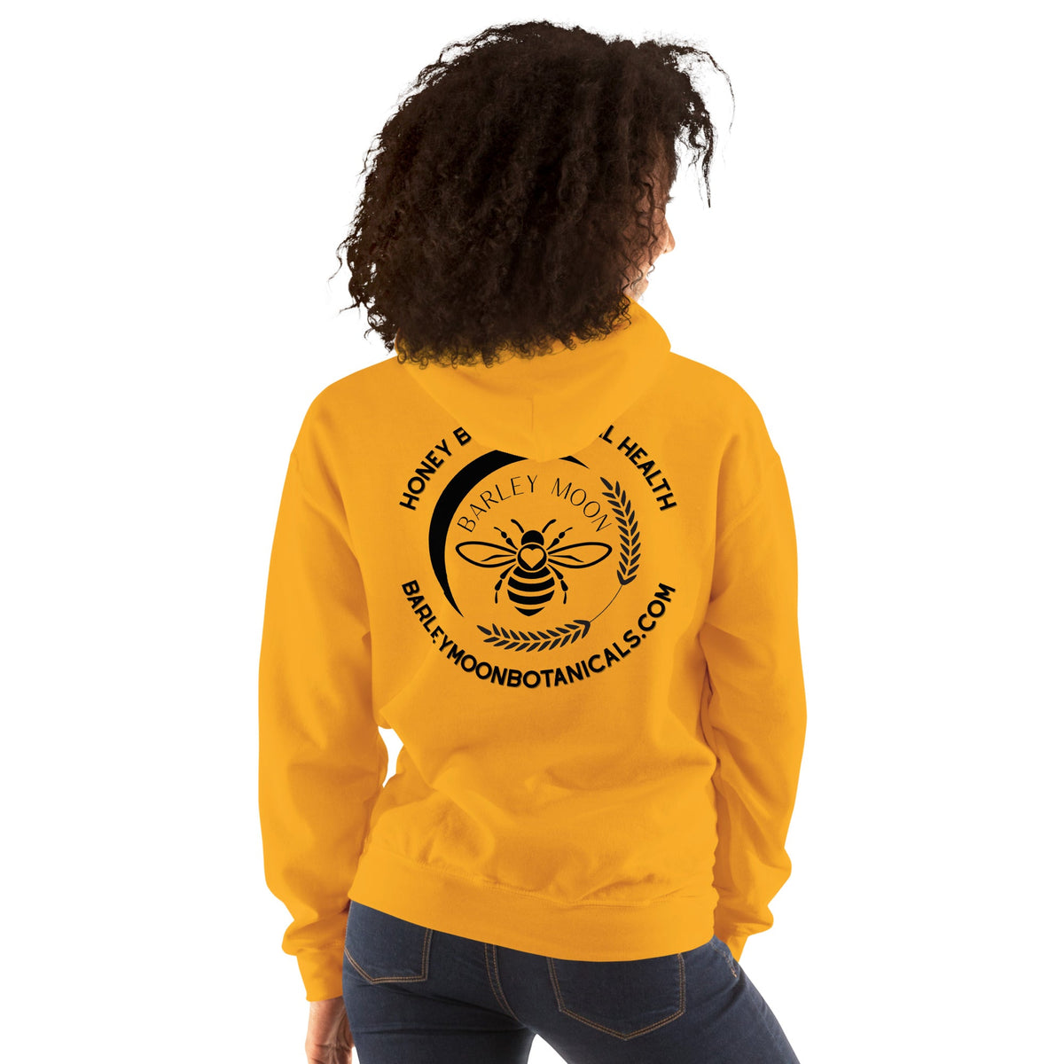 A person wearing a bright yellow Barley Moon Botanicals unisex hoodie with a black bee and moon logo on the back.