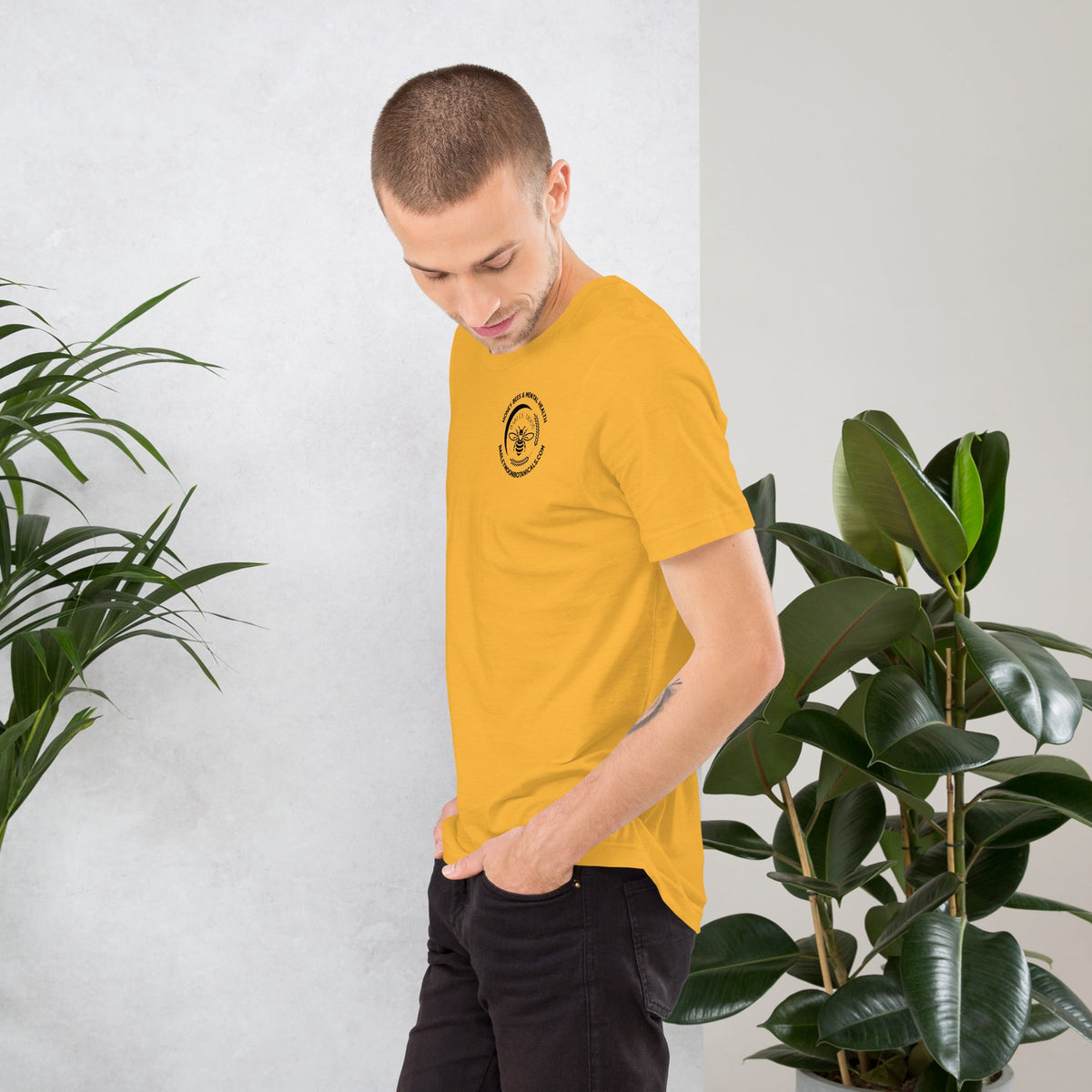 Barley Moon Botanicals unisex yellow t-shirt with a small bee logo on the chest, worn by a man in a studio setting.